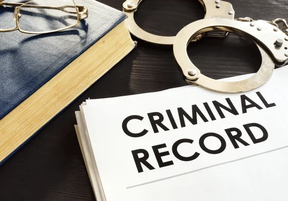 criminal-record-handcuffs-on-desk-600nw-1174972870